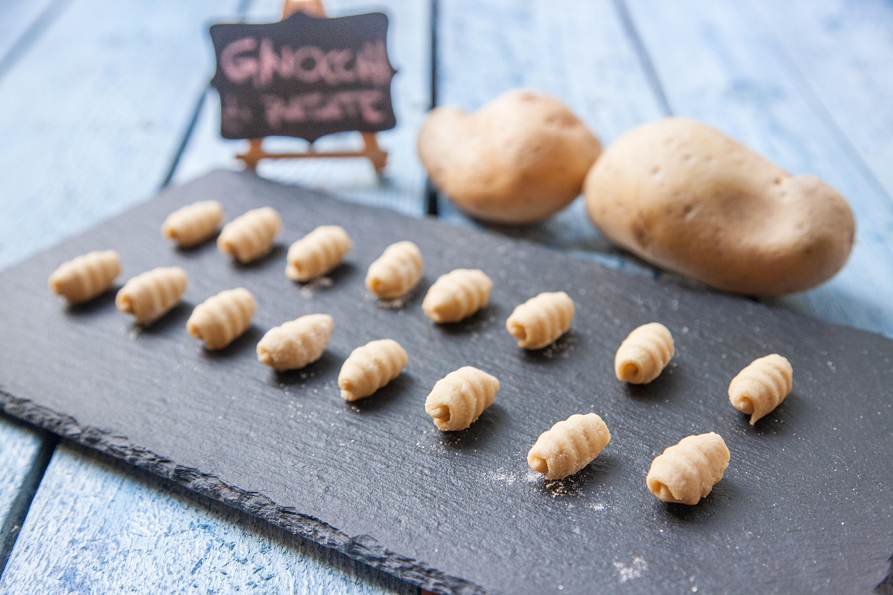 Gnocchi di patate freschi su un piano di lavoro con ingredienti e strumenti per la preparazione.