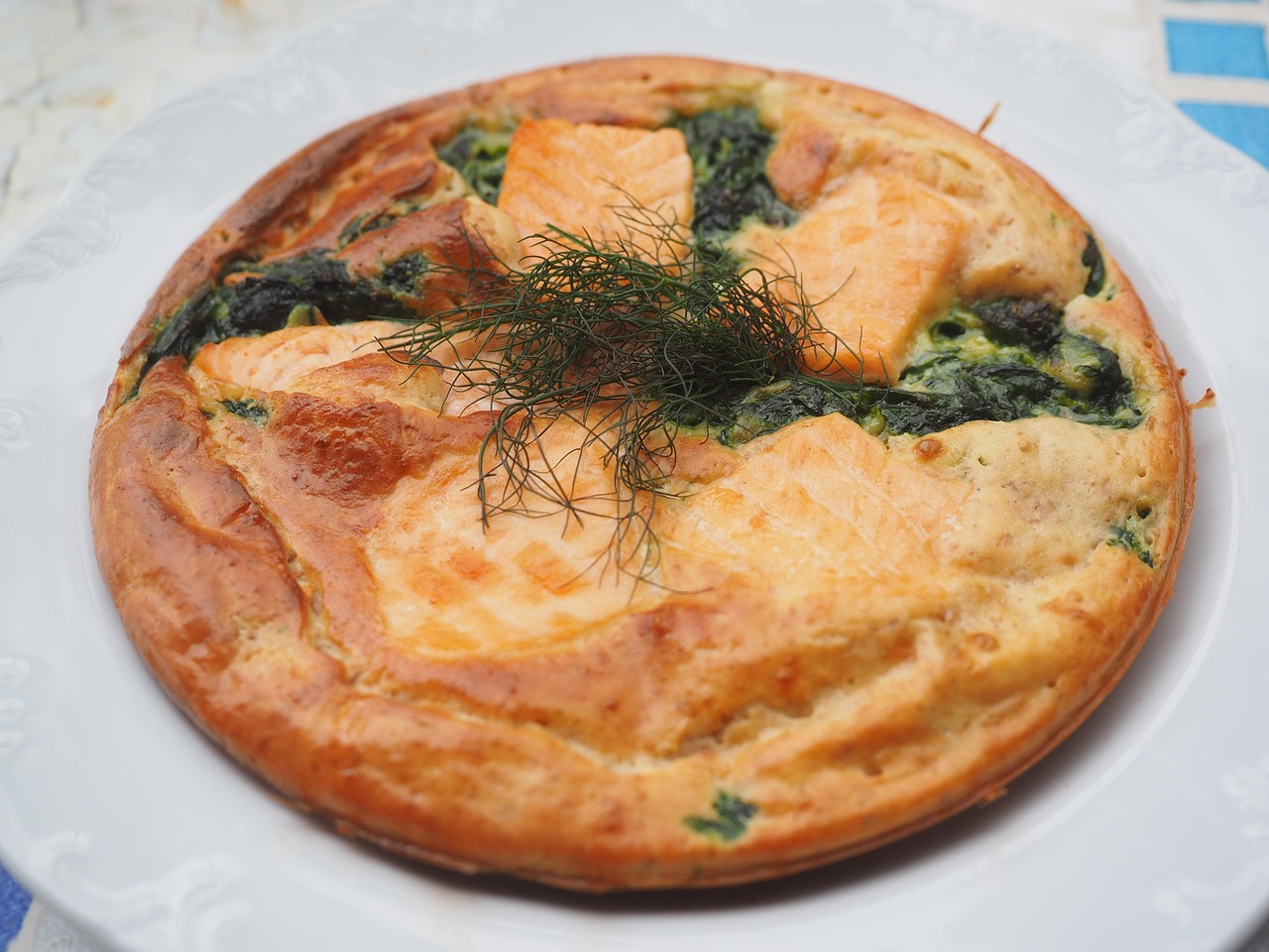 Frittata di spinaci e feta pronta, servita su un piatto bianco con verdure fresche sullo sfondo.