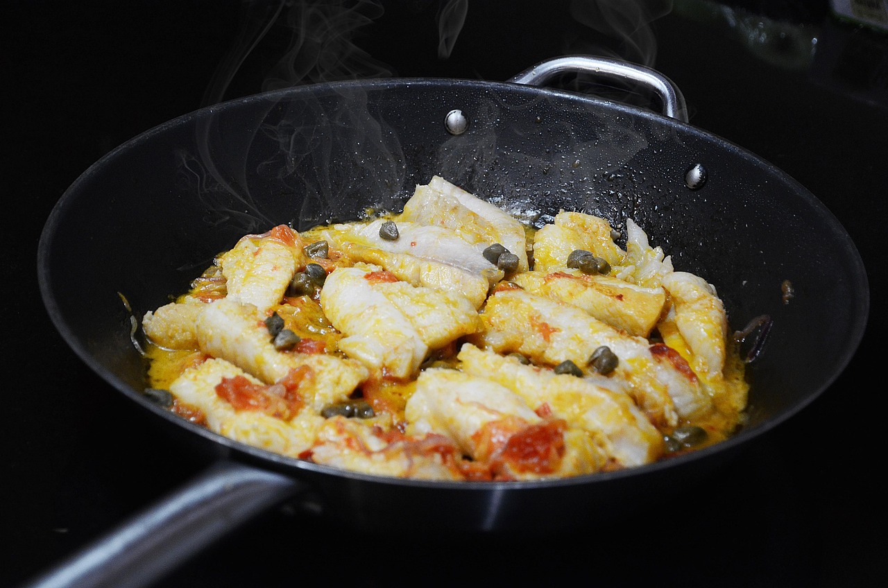 Baccalà alla vicentina cucinato, servito con contorni tipici e decorato con prezzemolo fresco.