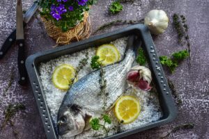 Branzino fresco su un tagliere, pronto per essere pulito e cucinato al sale.