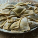 Ravioli freschi fatti in casa con ripieno cremoso su un tavolo di legno.