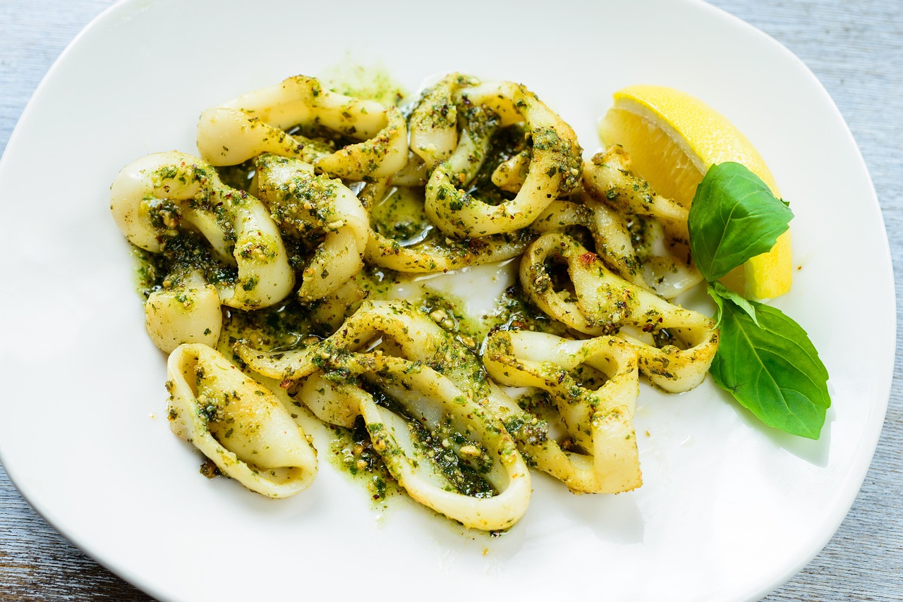 Calamari grigliati su un piatto, pronti da servire, con contorni freschi e decorazione di limone.
