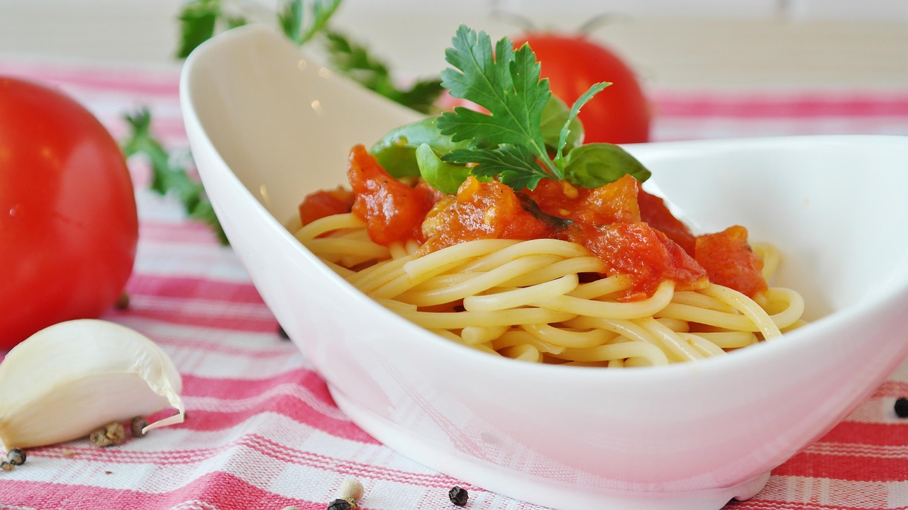 Pasta al pomodoro servita in un piatto, con foglie di basilico fresco.