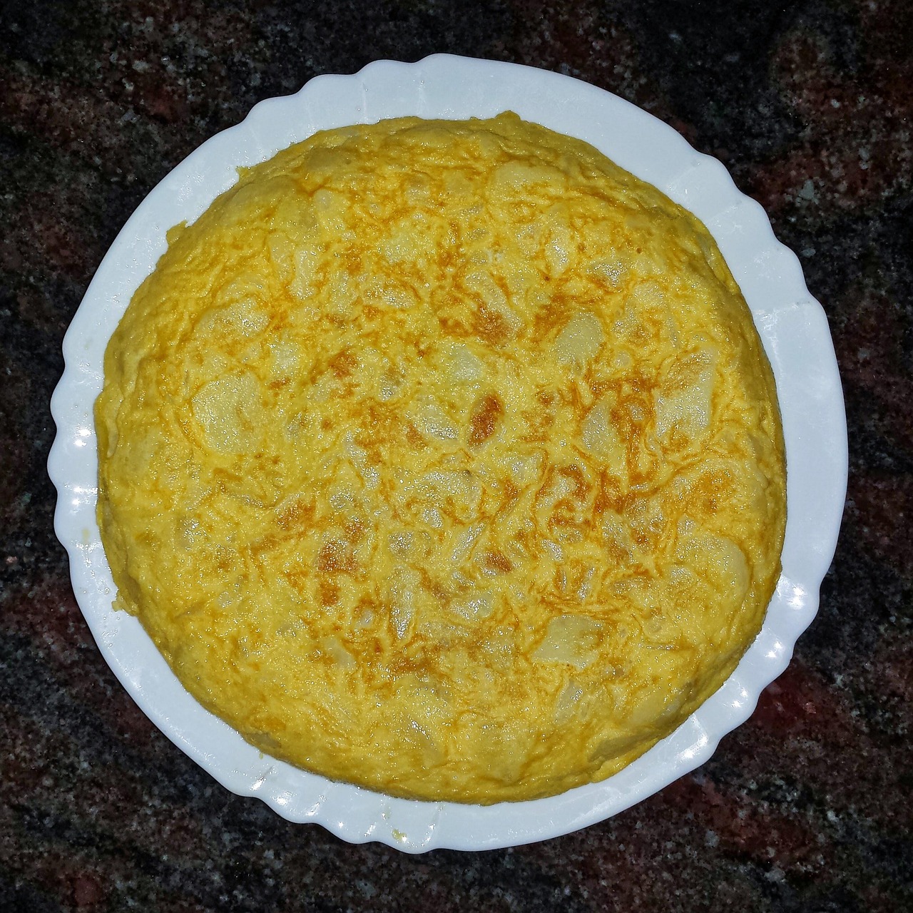 Frittata alta e soffice su un piatto, con erbe fresche e ingredienti colorati.