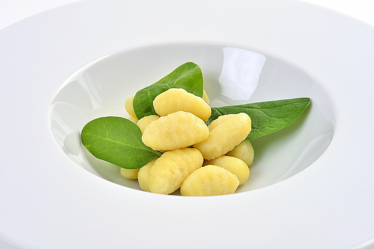 Gnocchi di spinaci e ricotta su un piano di lavoro con ingredienti freschi e attrezzi da cucina.