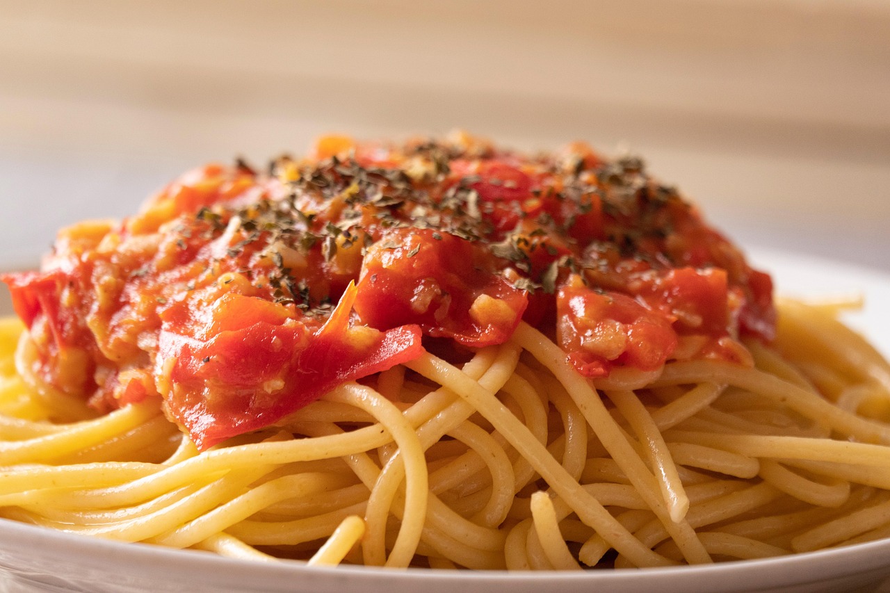 Pasta al pomodoro con sugo ricco, servita in un piatto elegante, decorata con basilico fresco.