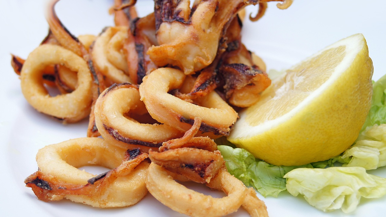 Calamari fritti su un piatto, con pastella croccante e limone a lato.