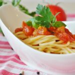 Pasta al pomodoro servita in una ciotola con misurino per calcolare le porzioni e gestire la glicemia.